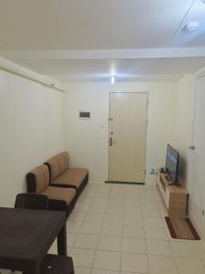 ein Wohnzimmer mit einem Sofa, einem TV und einer Tür in der Unterkunft Condo in Pasig in Manila