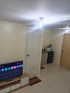 ein Wohnzimmer mit einem TV und einer Tür in der Unterkunft Condo in Pasig in Manila