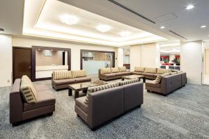 a lobby with couches and chairs and a television at Hotel Metropolitan Takasaki in Takasaki