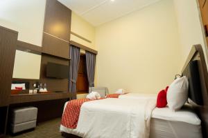 SentoolYuwono Hotel & Villa Malioboro的有两张床和一台电视的酒店房间