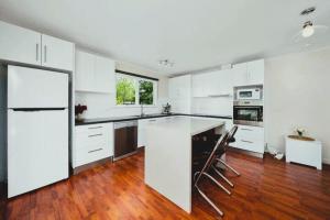 a large white kitchen with white cabinets and wooden floors at The Baker's Cottage in the Heart of Richmond Sleeps 6 in Hobart