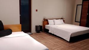 a hotel room with two beds with white sheets at JavaCove Beach Hotel in Batukaras +37 photos