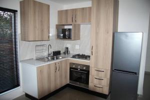 eine Küche mit Holzschränken und einem Edelstahlkühlschrank in der Unterkunft KT Nest in Midrand