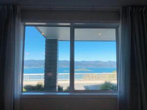 a window in a room with a view of the ocean at Stunning Seaviews in Wellington +10 photos