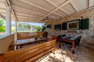 a dining room with benches and a table and a television at Olive Grove House in Ston