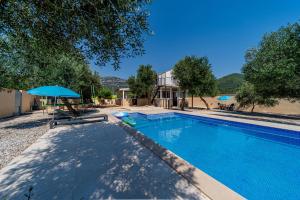 a swimming pool with a table and an umbrella at Olive Grove House in Ston