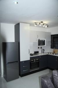 a kitchen with a black refrigerator and a sink at KT Space in Midrand