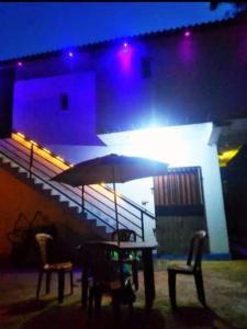 a table with chairs and an umbrella in front of a building at New Samanali Resort in Kataragama