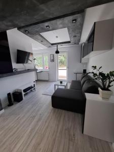 a living room with a black couch and a table at Przytulny 2-pokojowy apartament na wakacje w Gdańsku in Gdańsk