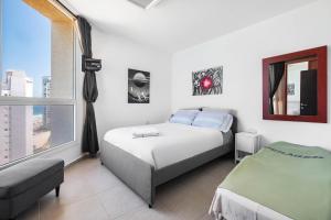 a white bedroom with a bed and a window at Amazing room + Private bathroom, Full sea view in Bat Yam