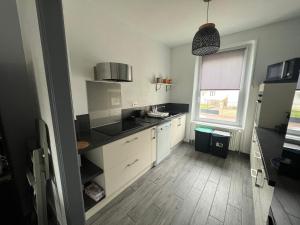 Blainville-sur-lʼEauにあるChez Nousの白いキャビネットと窓のあるキッチン