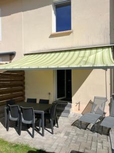 Blainville-sur-lʼEauにあるChez Nousの椅子とテーブルのあるパティオの上の緑の日よけ