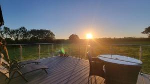 eine Terrasse mit Tisch und Stühlen und der Sonnenuntergang in der Unterkunft 18th century renovated barn in beautiful Devon countryside in Broadwoodwidger