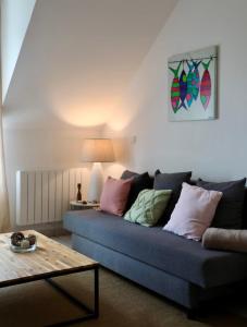 Una sala de estar con un sofá azul y una mesa. en Petit appartement calme vue sur havre de Carteret, en Barneville-Carteret