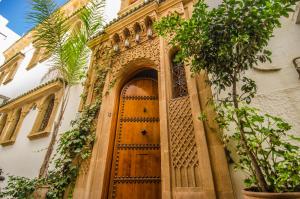 eine verzierte Holztür in einem Gebäude mit Pflanzen in der Unterkunft Riad Sidi Fatah in Rabat