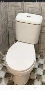 a white toilet in a bathroom with a tile floor at Agus Family Homestay in Labuan Bajo