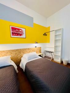 a bedroom with two beds and a yellow wall at ZAPPI CYCLING HOTEL in Riolo Terme