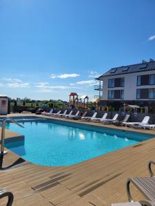 a swimming pool with lounge chairs and a building at Czar wakacji in Sarbinowo
