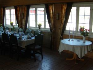 a dining room with tables and chairs and windows at Jækta Fjordstue in Mosvik
