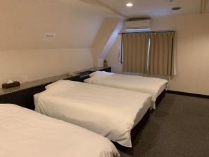 a hotel room with three beds with white sheets at 大阪グランドホテル Osaka Grand Hotel in Osaka