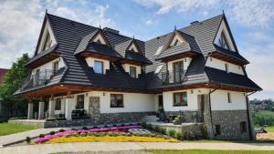 une grande maison avec un toit noir dans l'établissement Apartament Kohutówka, à Bukowina Tatrzańska