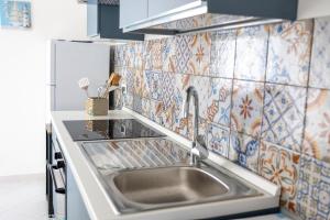 a kitchen with a sink and a tiled wall at Porto di Mare in Terrasini +78 photos