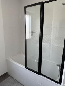 bañera blanca con puerta de ducha de cristal en Le Contrie - Bel appartement avec terrasse, en Nantes 9 fotos más