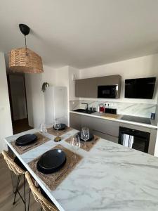 Una cocina con una mesa con platos y vasos encima. en Le Contrie - Bel appartement avec terrasse, en Nantes