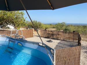 a swimming pool with an umbrella next to a fence at Casa the Dutchman in Navarrés
