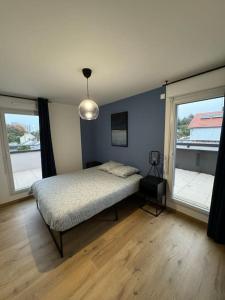 Un dormitorio con una cama y dos grandes ventanales. en Le Contrie - Bel appartement avec terrasse, en Nantes