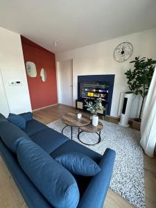 Una sala de estar con un sofá azul y una mesa. en Le Contrie - Bel appartement avec terrasse, en Nantes