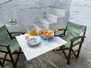 a white table with a bowl of food and two chairs at Kefalonia Alexis house in Pilaroú