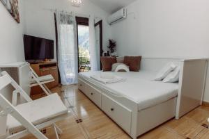 um quarto branco com uma cama e uma televisão em Zoi apartment em Kotor