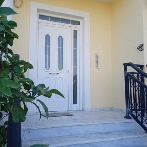 a white front door of a house with stairs at Anna's Apartment 4 - Sea View stay for 3 in Lixouri in Lixouri