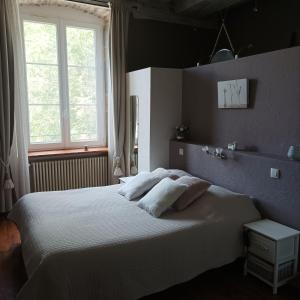 a bedroom with a white bed with two pillows at Maison d'Eusébia in Château-Chalon