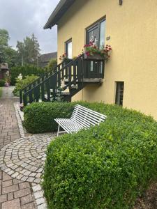 a white bench sitting in front of a house at Schöne Ferienwohnung im Grünen in Hainichen
