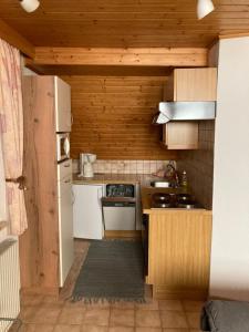 małą kuchnię z białymi urządzeniami i drewnianymi ścianami w obiekcie Ferienwohnung Steinwender w mieście Döbriach +16 zdjęć