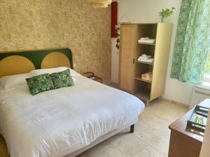 a bedroom with a bed with a green pillow on it at La rose du vent in Saint-Pons-de-Mauchiens