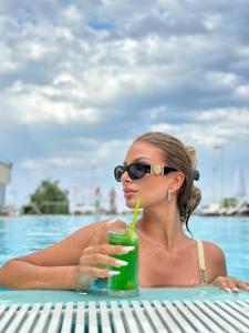 a woman in a swimming pool holding a drink at Hotel Queen Vera in Mamaia