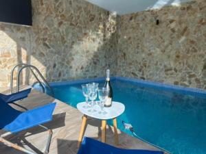 a table with glasses and a bottle of wine next to a swimming pool at Cabana Sofia in Moldoveneşti