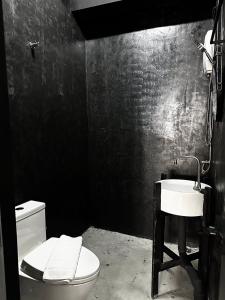 a black bathroom with a toilet and a sink at Sleep Owl Jomtien in Jomtien Beach