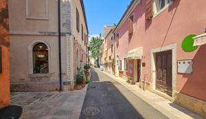 una strada vuota in una città con edifici rosa di Blu Violati a Novigrad Istria