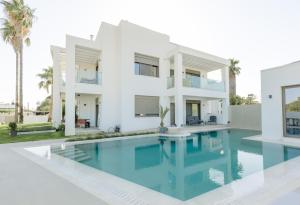 una casa bianca con una piscina di fronte di Palm View Suites a Kourouta