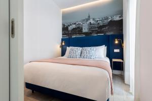 a bedroom with a large bed with a blue headboard at Apartamentos Sevilla Centro in Seville