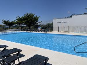 a large swimming pool with chairs and a building at Studio duplex face à la mer in Guidel