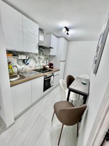 a kitchen with white cabinets and a table and chairs at A'MARE da Marco Loft in Sperlonga