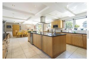 a large kitchen with wooden cabinets and a large island at Sleeps10 18-Parking-Garden-Pool-HotTub-Balcony in Eastbourne