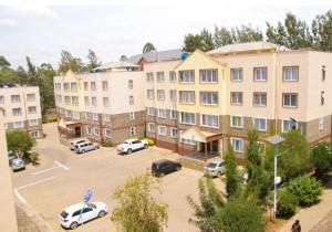 an apartment building with cars parked in a parking lot at Milimani Luxury Apartments - J1 in Nakuru