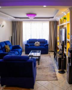 a living room with blue couches and a tv at Milimani Luxury Apartments - J1 in Nakuru