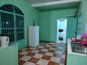 a kitchen with a white refrigerator and a checkered floor at Le DIEGO Hôtel in Antsiranana